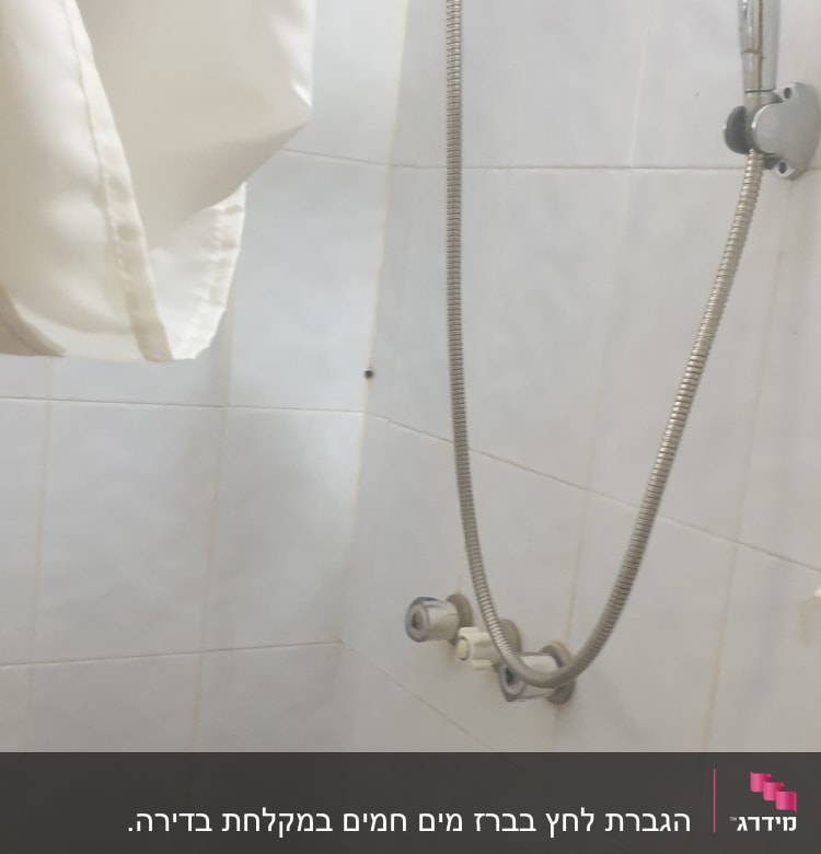 ראש מקלחת עם צינור גמיש על קיר אריחים